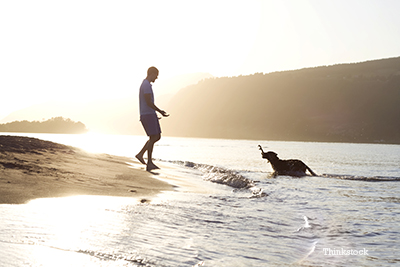 Man playing with his dog by the lake.