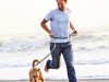 Man running on the beach with his dog