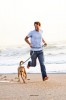 Man running on the beach with his dog